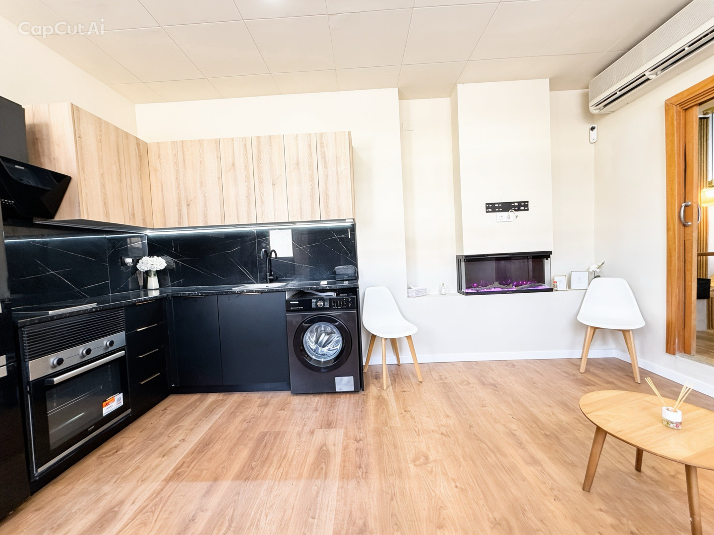Cocina equipada con horno, placa, lavadora y frente de mármol negro