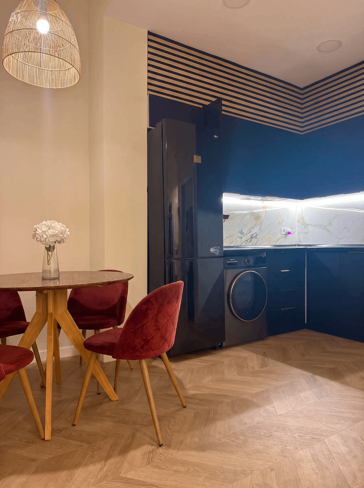 Cocina azul con frente de mármol, electrodomésticos integrados y comedor